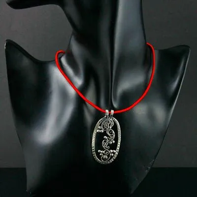 Elegant, oval pendant with four dancing paisley motifs and a garnet accent