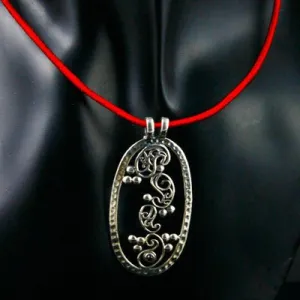 Elegant, oval pendant with four dancing paisley motifs and a garnet accent